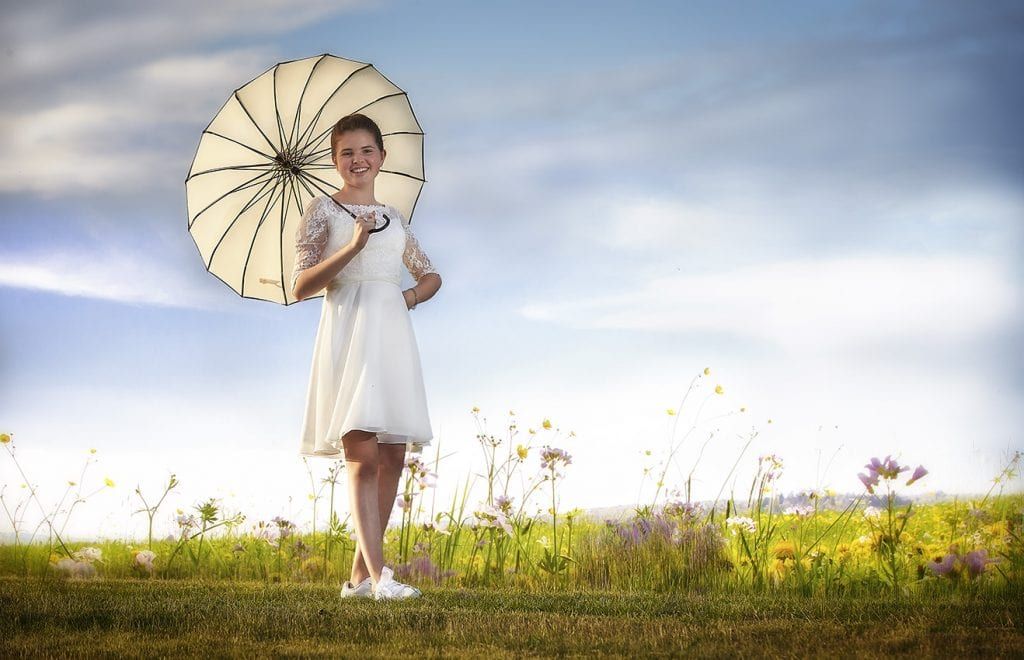 Konfirmand med parasol på en mark